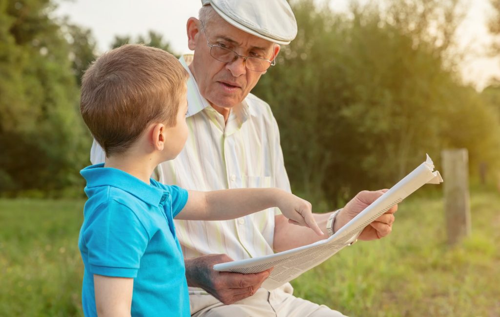 Senior man reading newspaper and cute child