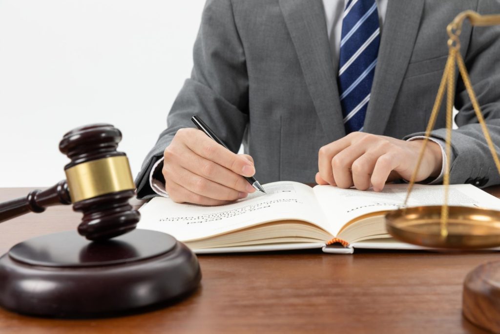 Person writing in a book with a gavel on the table