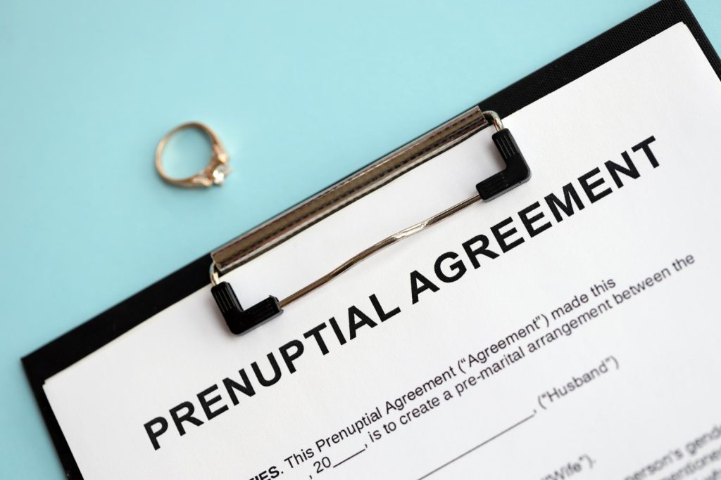 Prenuptial agreement and wedding ring on table